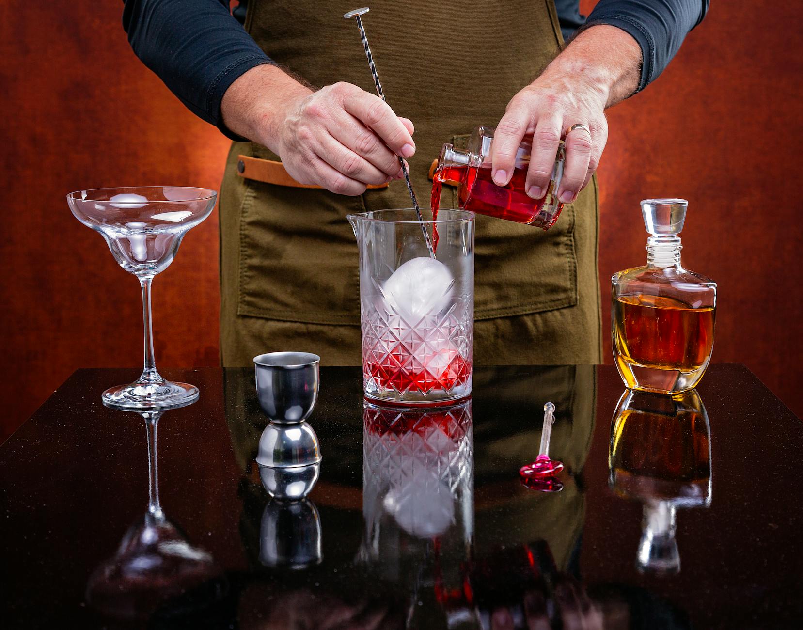 Jak zrobić idealne Negroni: proporcje, warianty i praktyczne wskazówki dla początkujących Barman przygotowuje koktajl Negroni z dużą kulą lodu
