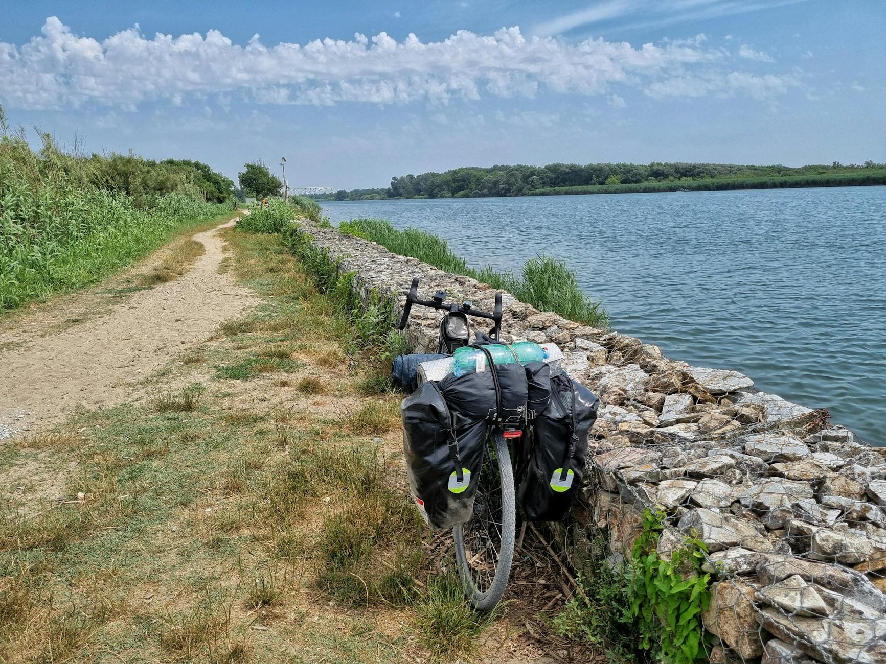 Rower z sakwami na wiejskiej ścieżce nad rzeką w Toskanii