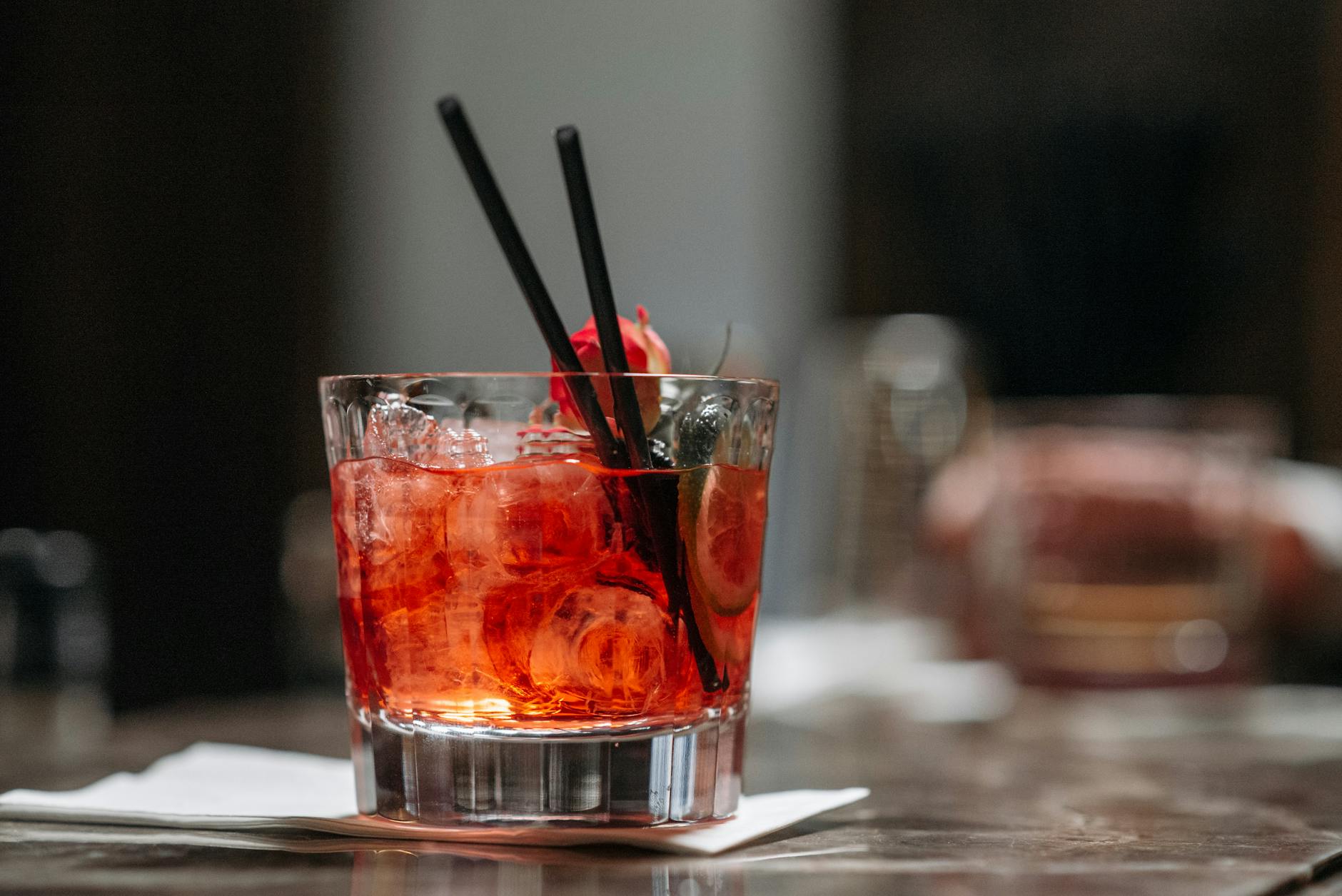 Szklanka Negroni z lodem i plastrem cytrusa na barze
