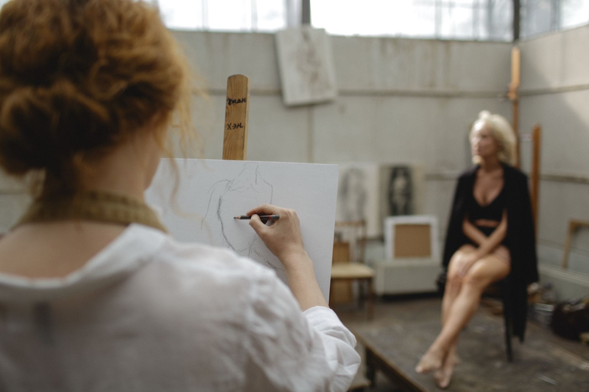 Artysta szkicuje pozującą modelkę w pracowni rysunku